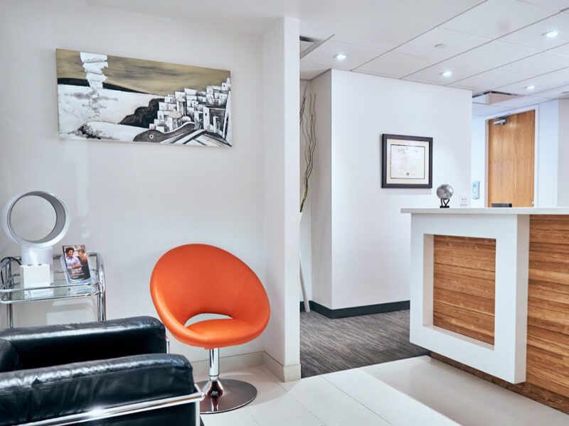 Modern office reception with orange chair and wooden desk.