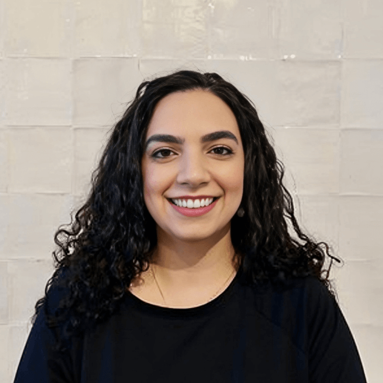 Smiling woman with curly hair in a black top against a light background.