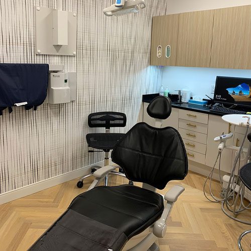 A modern dental office with a black dental chair and equipment.